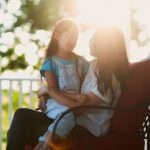Mother and daughter sitting together on a porch at sunset, having a heartfelt conversation—capturing the beauty of biblical, grace-filled communication in everyday moments.