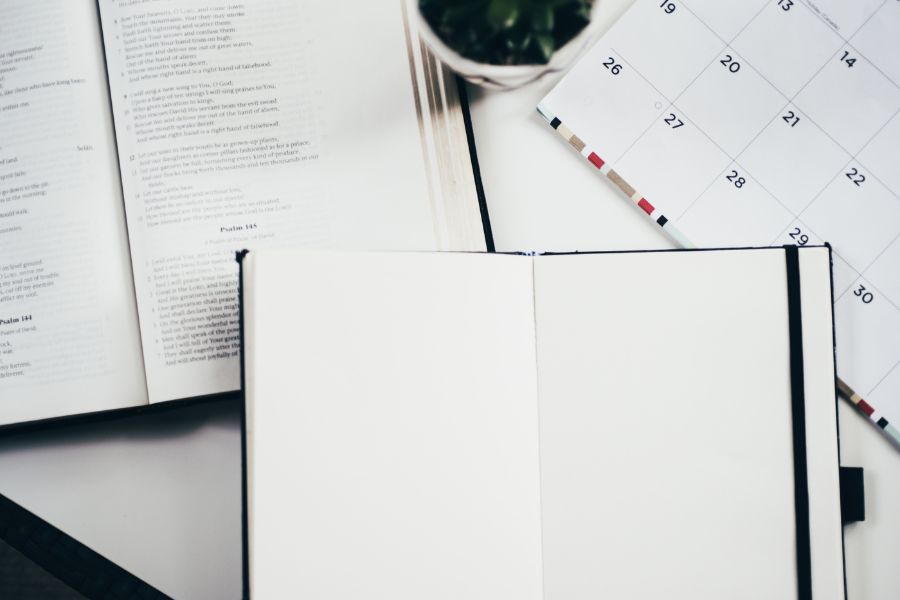 An open Bible, a blank journal, and a calendar, symbolizing time in God's Word, planning with intentionality, and anchoring priorities in Christ.