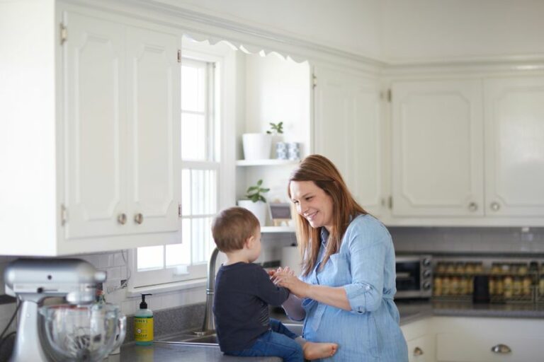 Mother smiling and spending time with her young child in a bright, cozy kitchen, reflecting warmth, love, and the joy of homemaking.