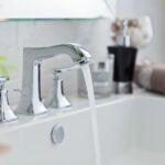 Clean white bathroom sink with running water, chrome faucet, and neatly folded towels—fresh and simple space ready after a deep clean