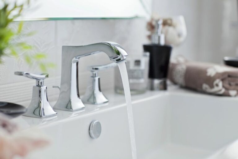 Clean white bathroom sink with running water, chrome faucet, and neatly folded towels—fresh and simple space ready after a deep clean