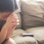 A woman quietly praying, seeking God's peace and strength in the midst of life's busyness