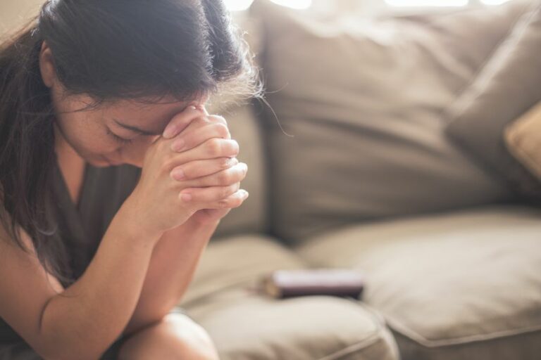 A woman quietly praying, seeking God's peace and strength in the midst of life's busyness