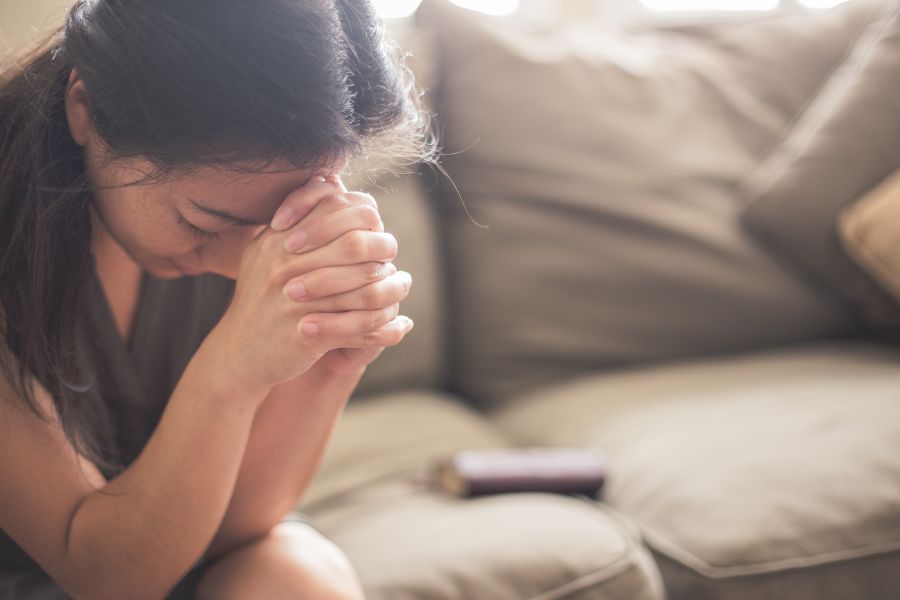 A woman quietly praying, seeking God's peace and strength in the midst of life's busyness