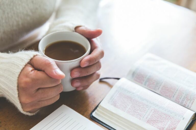 A woman holding a cup of coffee next to an open Bible and journal, reflecting on God’s faithfulness and trusting His work in the lives of others.